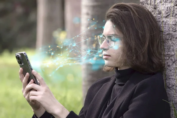a guy wearing glasses and business clothes holds a cell phone, looks at the screen with outgoing waves of holograms of information and neural connections transmitted to the brain. The concept of the Negative impact of AI on humans through Telecommuni