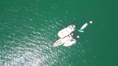 Güneşli bir günde gök mavisi deniz suyunda dönen tekne ve yatların insansız hava aracı videosu. Deniz yoluyla yaz seyahati. Denizde tatiller