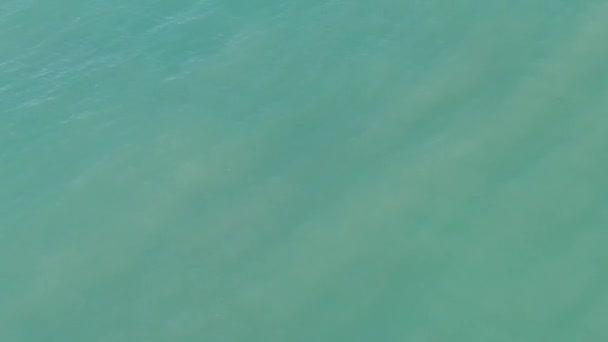 바다의 표면에 청록색 해안에 거품이 들어오는 파도의 시내의 위에서 있습니다 — 비디오