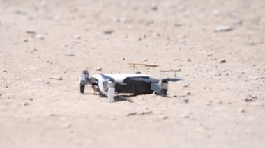Yavaş çekim sinemada bir dronun çölde havalandığını gösteren bir video. Drone kanatlarını döndürür ve yavaşça havalanır, yerden toz bulutları yükselir.