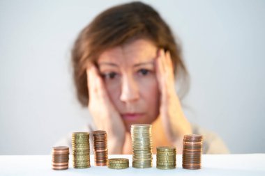 Kafasını elinde tutan bir adam hüzünlü para yığınlarına bakar. Şaşkınlık, endişe, çaresizlik, parasızlık stresi. Ekonomik sorunlar, finansal kriz, nakit tasfiye