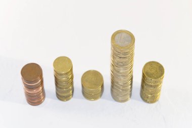 Beyaz arka planda farklı seviyelerde altın sikkeler var. Finansal büyüme ve yatırım başarısı kavramı.