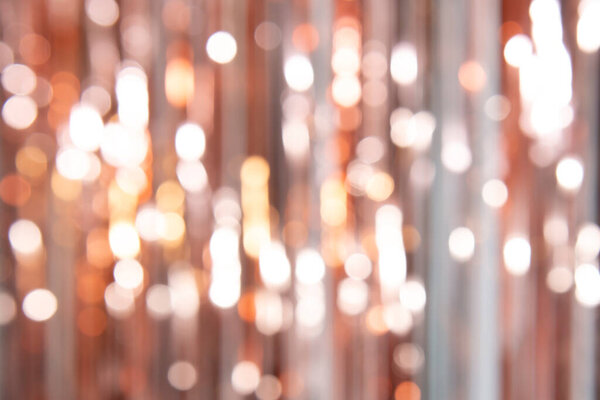 A festive background in a delicate powdery color made of bokeh, glare and blurry spots from the shine of the rain from their foil. Abstraction from blur, lines, bokeh of pastel halftones