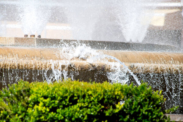 City fountain in a sunny cityscape in the heat.Clouds of splashes, drops and jets of a fountain close-up glisten in the sun's rays. The coolness of a summer fountain