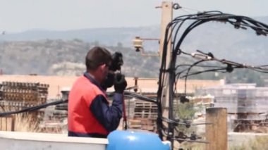 Elektrik hatlarında bakım yapan bir elektrikçi, yüksek ısıda asansörden koruyucu ekipman ve aletler kullanıyor, video sıcak havanın hareketini gösteriyor. Yüksek sıcaklıklarda çalışıyor.