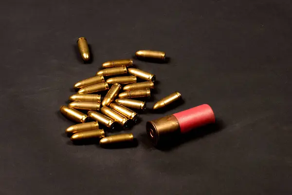 stock image A group of pistol bullets and a rifle cartridge from a shotgun shotgun on a dark background. Ammunition in storage. Military attributes