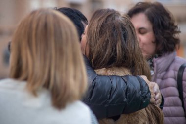 İnsanlar dışarıda birbirlerine sarılıp selamlıyorlar. Arkadaşlar buluşması, olumlu anlar, bağlanma, birliktelik.