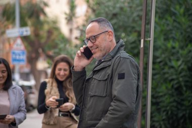 Bir grup insan aynı anda hem telefonda konuşuyor hem de izliyor. İletişim, bağlanma, bağlantı, arkadaşlar cep telefonuyla sohbet