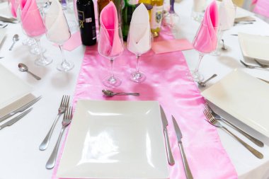 Tabaklar, peçeteler ve pembe saten ayaklı bardaklarla yemek masası. Restoranda yemek servisi. Tatil ya da ziyafet için.