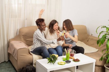 Arkadaşlar sohbet ediyor, sıcak bir oturma odasında gülüyor, arkadaşlıktan, sağlıklı yiyeceklerden ve içeceklerden keyif alıyorlar. Sosyal iletişim