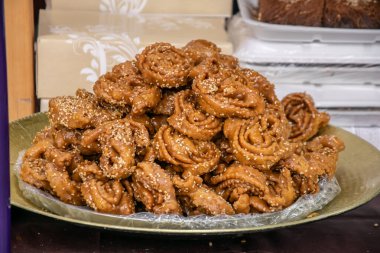 Yiyecek pazarı vitrininde susam tohumlarıyla kaplanmış geleneksel kızarmış tatlı hamur işleriyle dolu büyük bir tabak. yüksek kalorili ürün,