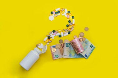 Avro banknotları ve sikkelerin yanında soru işareti şeklinde dağıtılmış haplar. Sağlık ve ilaçların verimliliğine mal oldu. Eczacılık sektörü sağlığı