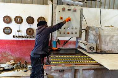 Esmer tenli Afrikalı adam atölyedeki fabrikada fayanslarla çalışıyor. Canlı iş gücü ve makinelerle mekanize işlem üretiliyor