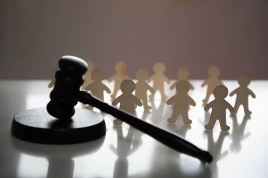 Yargıcın tokmağı bir grup insan figürünün önünde yatıyor. Yasal karar kavramı, toplum için yasalar. Kanunun gücünü sınırlayarak insanların kontrolü ve manipülasyonu. Komplo teorisi ve disiplin.