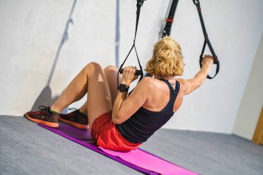 Bir kadın direniş bandıyla egzersiz yapıyor. O, siyah bir atlet ve kırmızı bir şort giyiyor. Fitness konsepti.