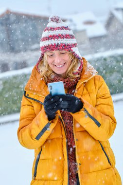 Beyaz bir kadın kışın açık havada karda cep telefonuyla eğleniyor. Navarre, İspanya, Avrupa.