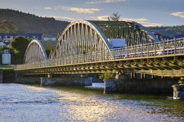 Steel bridge with arches crossing a calm river at sunset. Colindres, cantabria, spain clipart