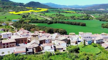 Bereketli yeşil tarlalar ve yuvarlanan tepelerle çevrili, güneş ışığıyla yıkanmış sakin bir köy. Iguzkiza, Navarre, İspanya. İHA görüntüsü. Yüksek kalite 4k görüntü