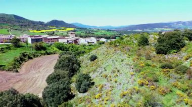 Soluk kesici drone perspektifi yuvarlanan tepeler ve yemyeşil yeşillikler arasında geleneksel bir İspanyol köyünün güzelliğini gözler önüne seriyor. Iguzkiza, Navarre, İspanya. Yüksek kalite 4k görüntü