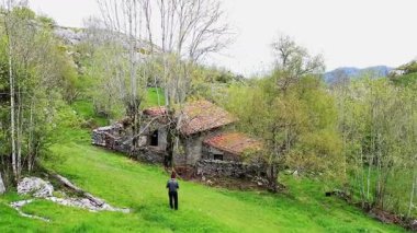 Terk edilmiş eski bir kulübeyi ve ağaçları izleyen bir adam. Soba vadisi, Cantabria, İspanya. Yüksek kalite 4k görüntü