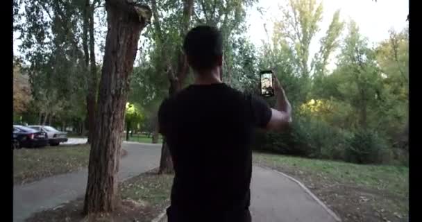 Fekete Edzőruhába Öltözött Izmos Lábú Fiú Használja Telefonját Őszi Szezonban — Stock videók