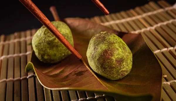 Green tea balls for desserts, delicious Japanese food with black background and decorated with leaves and a wicker basket, for oriental and Asian food restaurant.
