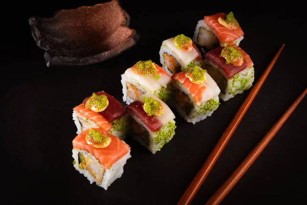 Japanese sushi, delicious Japanese food with black background and decorated with seeds and soy sauce, for oriental and Asian food restaurant.