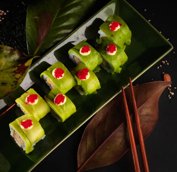 Aerial Shot Japanese Urumaki sushi roll forest, delicious Hawaiian food with black background and decorated with a bowl of soy sauce, for oriental and Asian food restaurant.
