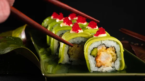 Beautiful Japanese Urumaki sushi roll forest, delicious Hawaiian food with black background and decorated with a bowl of soy sauce, for oriental and Asian food restaurant.