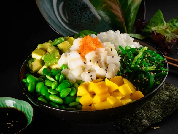 Poke , delicious Hawaiian food with black background and decorated with chopsticks and a bowl of soy sauce ,for oriental and Asian food restaurant.