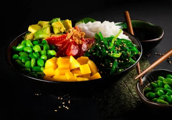 Poke , delicious Hawaiian food with black background and decorated with chopsticks and a bowl of soy sauce ,for oriental and Asian food restaurant.
