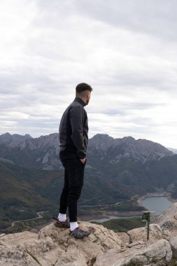 Genç dağcı dağın tepesinde karanlık dağ kıyafetleri içinde köpeğinin yanındaki bir kayanın üzerinde dinleniyor. Arka planda bir göl ve komşu sıradağları görebiliyoruz. Yürüyüş ve tırmanış için duvar kağıtları