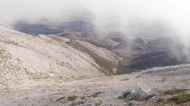 冬の霧に囲まれた2つの山の間を進むドローンの空中ショットは 背景には冬の暖かい色を持つ森を見ることができます 山の空中ドローンビュー — ストック動画