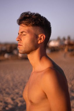 Yakın plan, çekik gözlü ve çenesi açık genç bir çocuk plajda tatil gününde gözlerini kapadığında eğleniyor ve rahatlıyor..