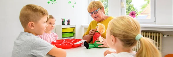 Children speech therapy concept. Children practicing correct pronunciation with a female speech therapist. Group therapy banner.