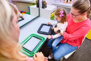 Serebral felçli sözsüz bir kız iletişim kurmak için dijital tablet kullanmayı öğreniyor. Dil geliştirmede zorlanan ya da konuşma aygıtı kullanan insanlar.