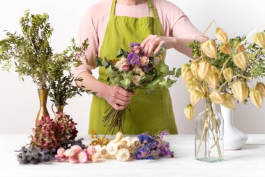 Kurumuş çiçekler. Dişi çiçekçi kurumuş çiçekleri güzel bir bukete yerleştiriyor. Sürdürülebilir çiçekçilik. Kurumuş çiçeklerle ev dekorasyonu oluşturuluyor.