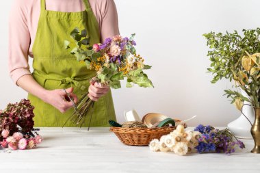 Kurumuş çiçekler. Dişi çiçekçi kurumuş çiçekleri güzel bir bukete yerleştiriyor. Sürdürülebilir çiçekçilik. Kurumuş çiçeklerle ev dekorasyonu oluşturuluyor.