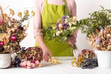 Kurumuş çiçekler. Dişi çiçekçi kurumuş çiçekleri güzel bir bukete yerleştiriyor. Sürdürülebilir çiçekçilik. Kurumuş çiçeklerle ev dekorasyonu oluşturuluyor.