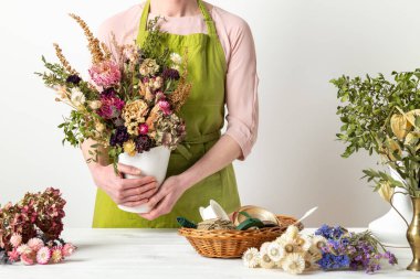 Kurumuş çiçekler. Dişi çiçekçi kurumuş çiçekleri güzel bir bukete yerleştiriyor. Sürdürülebilir çiçekçilik. Kurumuş çiçeklerle ev dekorasyonu oluşturuluyor.
