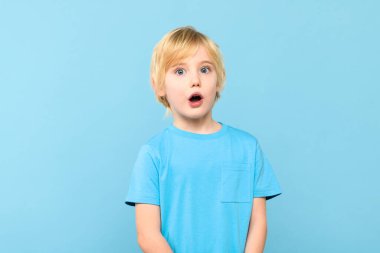 Vay canına! Şok olmuş, sarı saçlı, ağzı açık, tek eliyle pastel mavisi arka planda bir çocuğun portresi. Anaokulu öğrencisinin şutu..