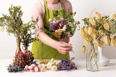 Kurumuş çiçekler. Dişi çiçekçi kurumuş çiçekleri güzel bir bukete yerleştiriyor. Sürdürülebilir çiçekçilik. Kurumuş çiçeklerle ev dekorasyonu oluşturuluyor.