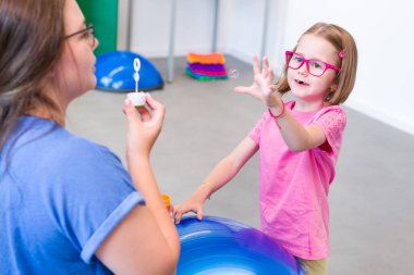 Karşılıklı koordinasyon fizyoterapisinde fiziksel engelli bir çocuk. Serebral felçli bir çocuk fizyoterapi sırasında terapistiyle egzersiz yapıyor..