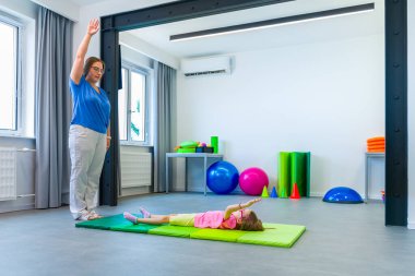 Fizik tedavi seansında fiziksel engelli bir çocuk. Serebral felçli bir çocuk fizyoterapi sırasında terapistiyle egzersiz yapıyor..