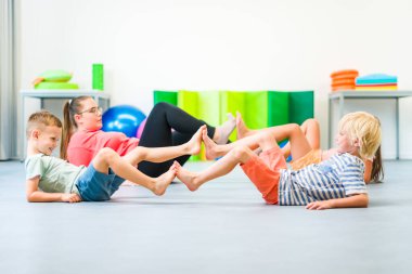 Küçük çocuklar grup terapisi sırasında kadın fizyoterapistle egzersiz yapıyorlar. Çocuk mesleği fizyoterapisi. Çift taraflı koordinasyon.