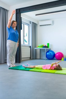 Fizik tedavi seansında fiziksel engelli bir çocuk. Serebral felçli bir çocuk fizyoterapi sırasında terapistiyle egzersiz yapıyor..