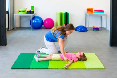 Fizik tedavi seansında fiziksel engelli bir çocuk. Serebral felçli bir çocuk fizyoterapi sırasında terapistiyle egzersiz yapıyor..