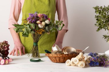 Kurumuş çiçekler. Dişi çiçekçi kurumuş çiçekleri güzel bir bukete yerleştiriyor. Sürdürülebilir çiçekçilik. Kurumuş çiçeklerle ev dekorasyonu oluşturuluyor.