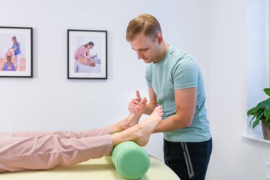 Fizik tedavide ayak bileği ağrılı bir kadın. Kayropraktik uzmanı yaralı ayak bileği eklemlerini muayene ediyor..
