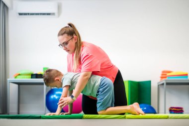 Terapi seansı sırasında fizyoterapistle egzersiz yapan genç bir çocuk. Çocuk fizyoterapisi. Çift taraflı koordinasyon.